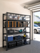 Steel shelving in a NZ garage holding labelled tubs, power tool cases and camping gear